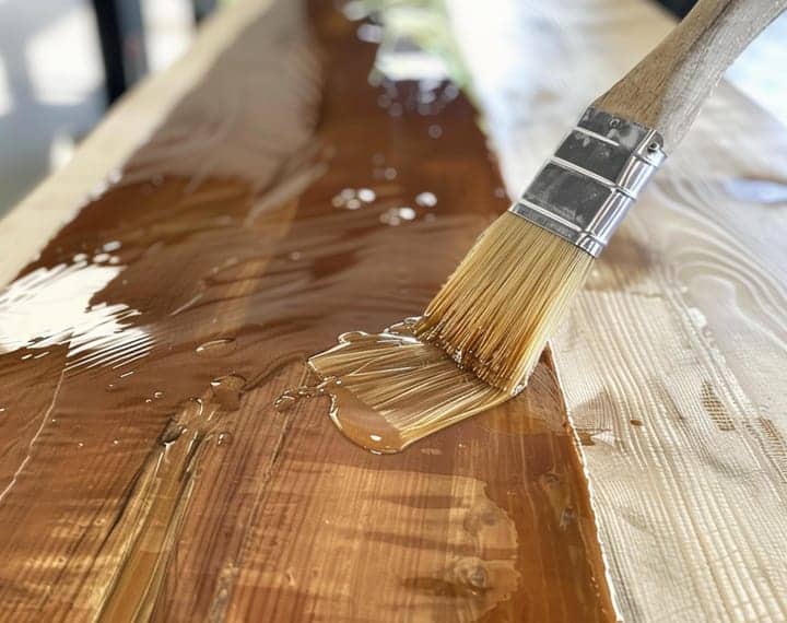 Pincel barnizando madera clara con brillo