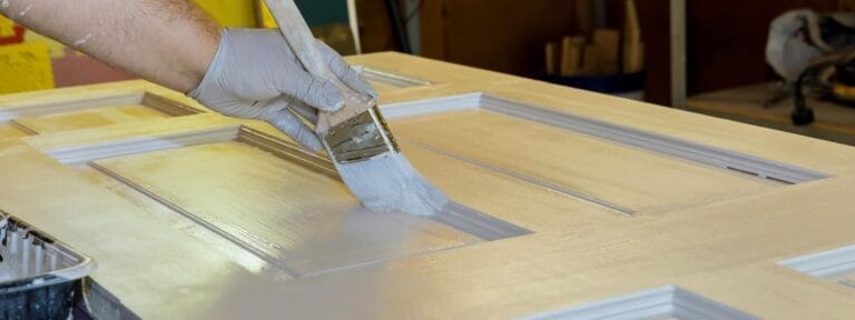 Pintando una puerta de madera con brocha.